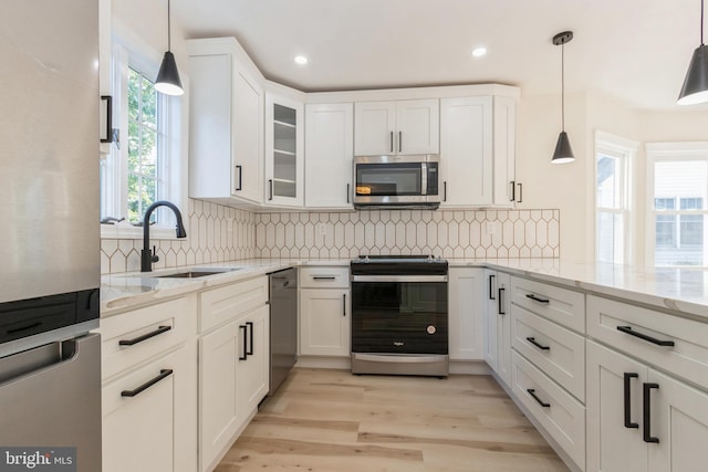 kitchen featuring appliances with stainless steel finishes, a healthy amount of sunlight, white cabinets, and hanging light fixtures