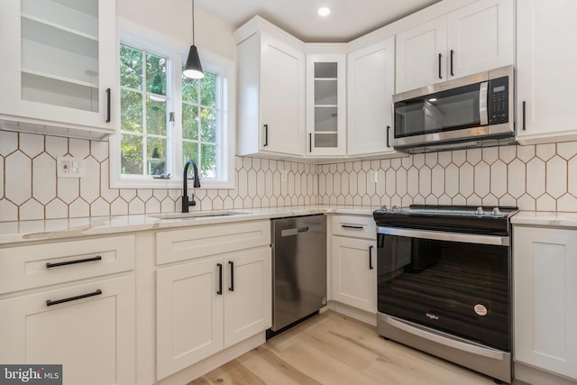 kitchen with appliances with stainless steel finishes, hanging light fixtures, sink, and decorative backsplash