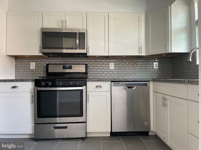 kitchen featuring dark stone countertops, white cabinetry, and stainless steel appliances