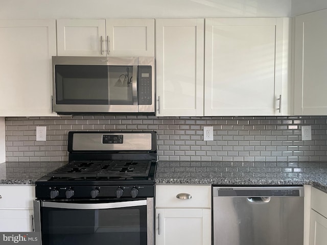 kitchen featuring dark stone countertops, stainless steel appliances, white cabinets, and decorative backsplash