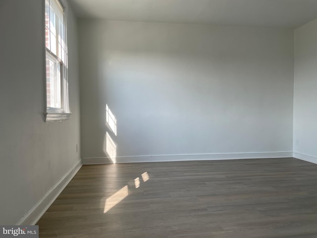 unfurnished room featuring dark wood-type flooring and a healthy amount of sunlight