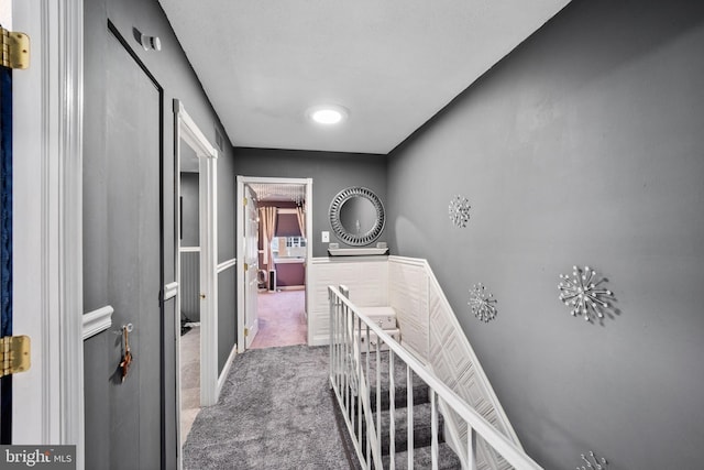 corridor featuring an upstairs landing and carpet flooring