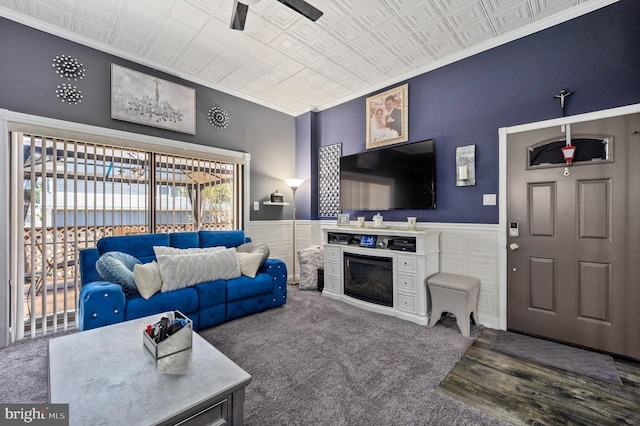 living area with a wainscoted wall, carpet flooring, an ornate ceiling, and crown molding