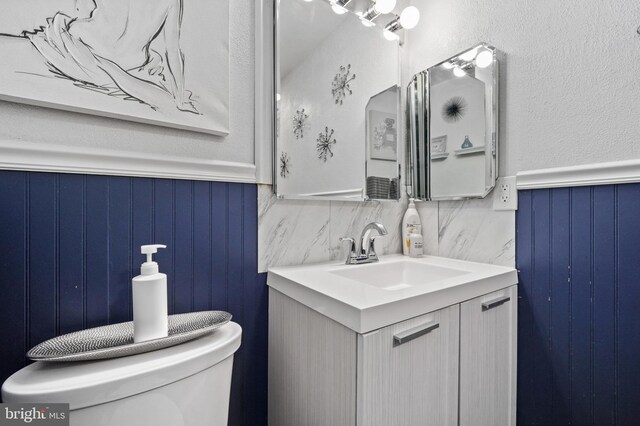 bathroom featuring vanity, toilet, and tasteful backsplash