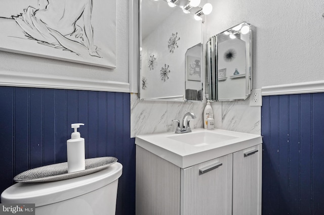 bathroom featuring vanity, wainscoting, and toilet