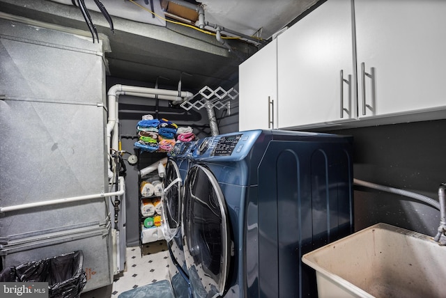 washroom featuring a sink, a garage, cabinet space, and washing machine and clothes dryer