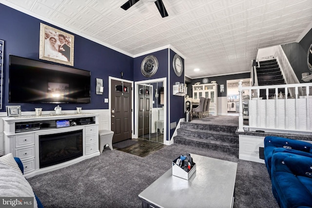 living room featuring stairway, a wainscoted wall, a fireplace, an ornate ceiling, and crown molding