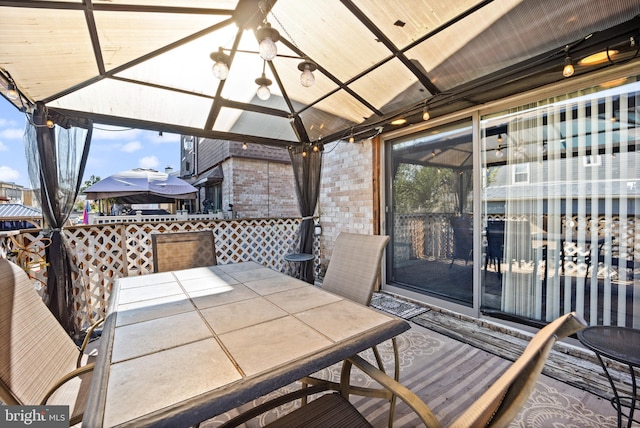 wooden terrace featuring a gazebo and outdoor dining area