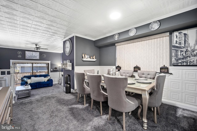 dining area featuring crown molding, ceiling fan, and dark colored carpet