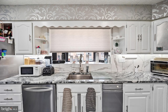 kitchen with white cabinets, dark stone countertops, dishwasher, and sink