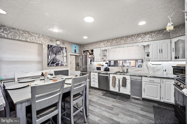 kitchen with light stone countertops, white cabinetry, stainless steel appliances, and dark hardwood / wood-style flooring