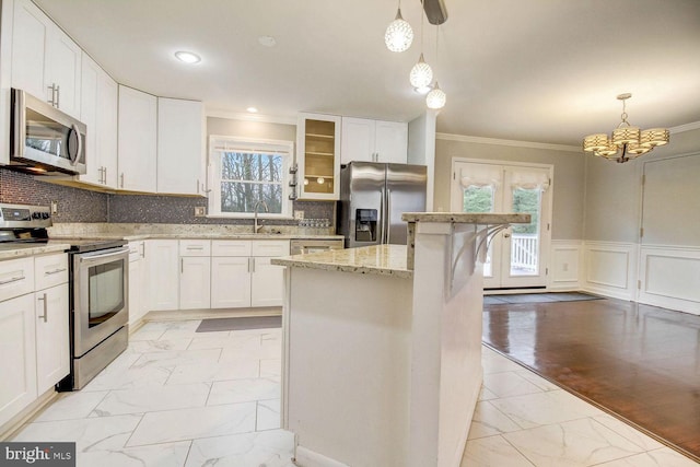 kitchen featuring appliances with stainless steel finishes, backsplash, pendant lighting, white cabinets, and a center island