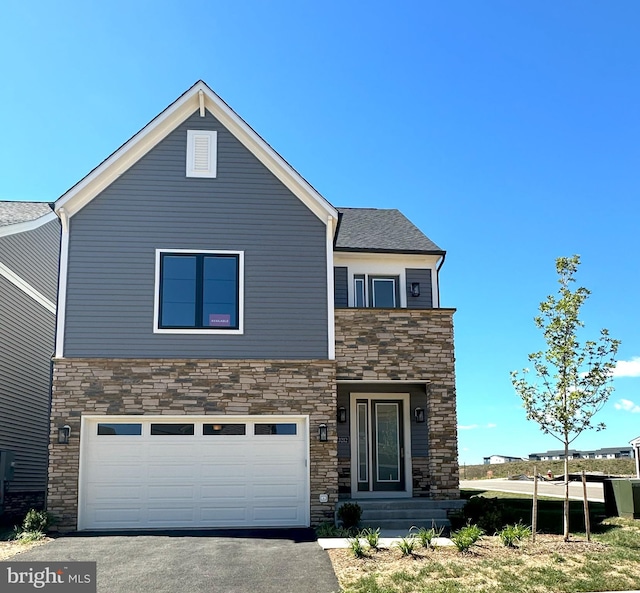 view of front facade with aphalt driveway, stone siding, and an attached garage