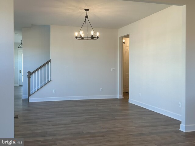 empty room with an inviting chandelier and dark hardwood / wood-style flooring