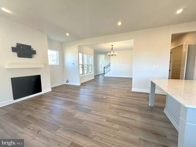 unfurnished living room with wood-type flooring and a notable chandelier