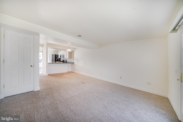 unfurnished living room with light colored carpet and sink