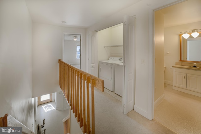 corridor featuring washing machine and clothes dryer, light carpet, and sink