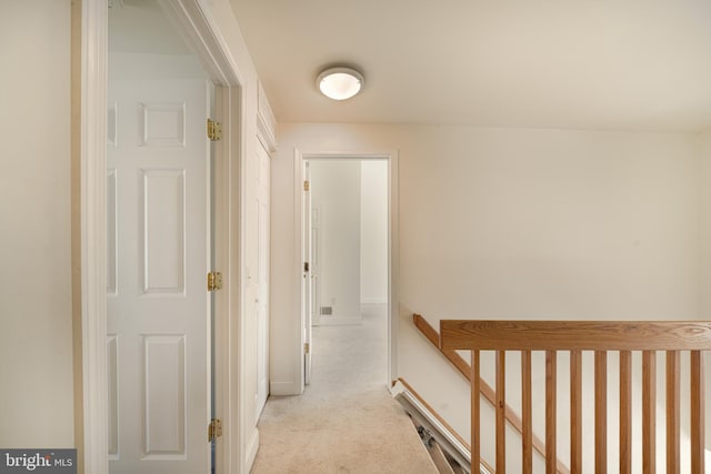 hall with baseboards, carpet, and an upstairs landing