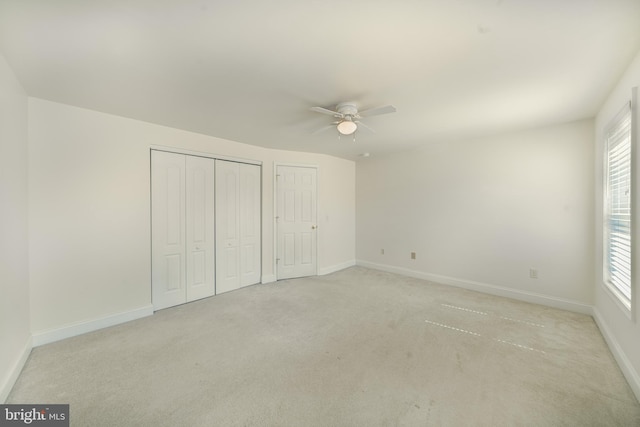 unfurnished bedroom with light carpet, two closets, and ceiling fan