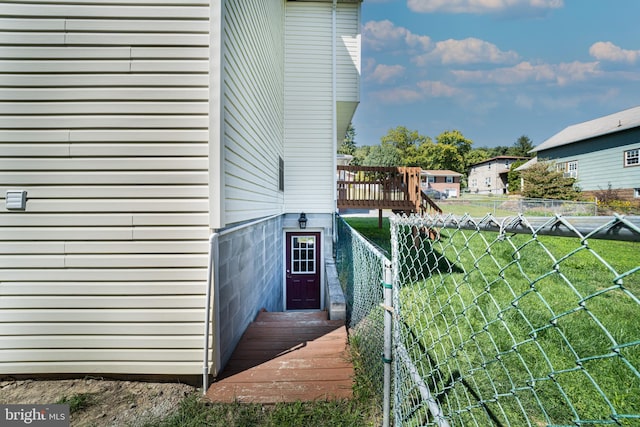 view of side of property with a yard, a wooden deck, a chimney, and fence