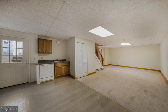 bar with baseboards, light wood finished floors, white dishwasher, a sink, and stairs