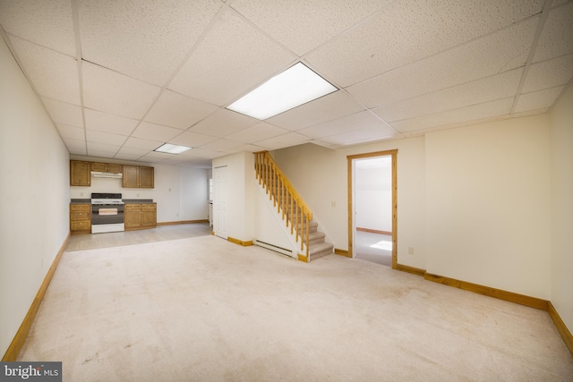 finished below grade area featuring a drop ceiling, light colored carpet, stairs, and baseboards