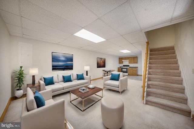 living room featuring a drop ceiling, baseboards, light colored carpet, and stairs