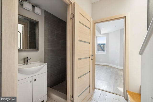 bathroom with wood-type flooring, vanity, and tiled shower