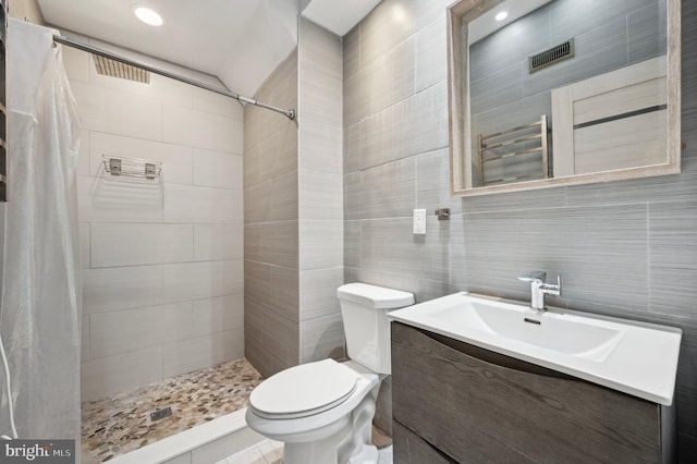 bathroom featuring toilet, vanity, tile walls, and walk in shower