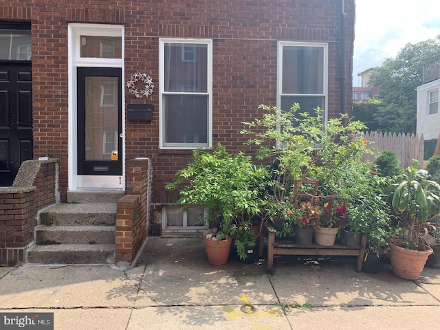 entrance to property with fence and brick siding