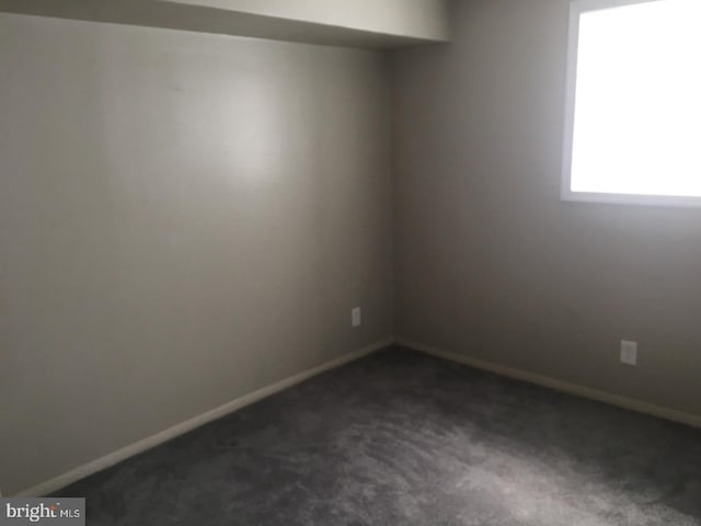 empty room with dark colored carpet and baseboards