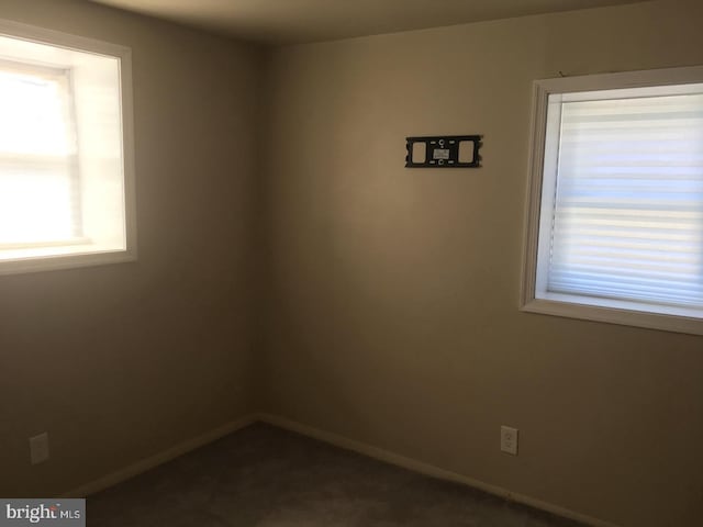 empty room with dark colored carpet and baseboards