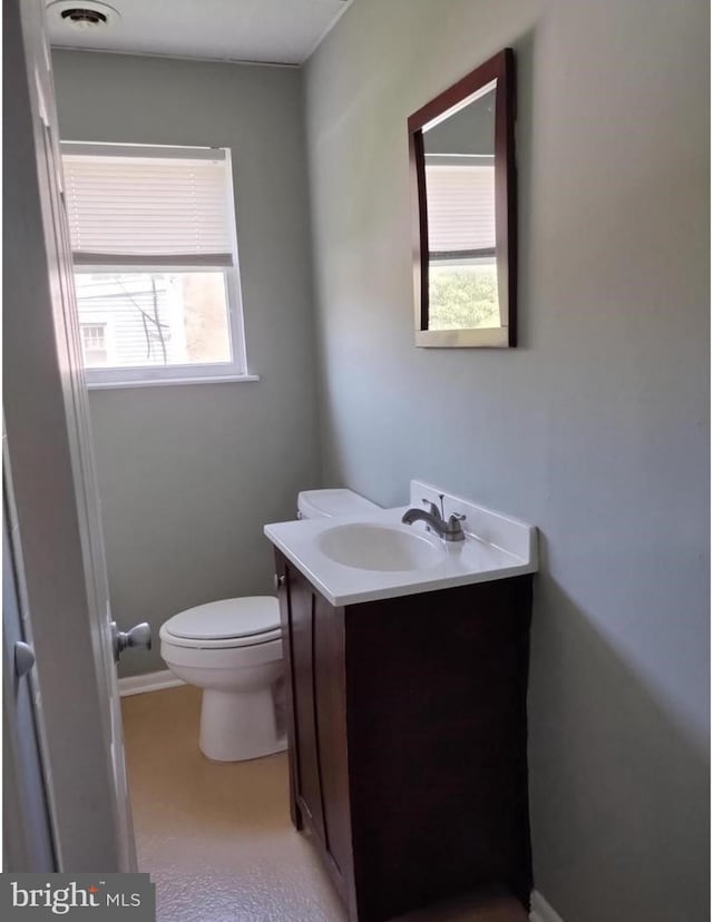 bathroom with vanity, toilet, and a healthy amount of sunlight