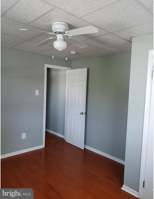 unfurnished room with a paneled ceiling, ceiling fan, and dark hardwood / wood-style flooring