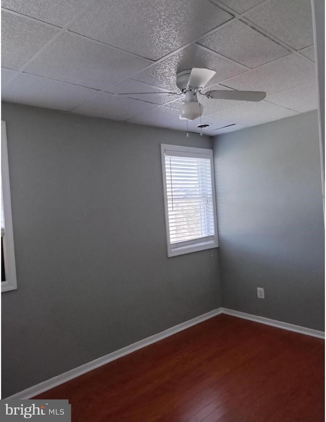 unfurnished room with wood-type flooring, ceiling fan, and a drop ceiling