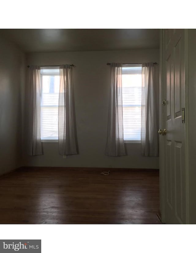 spare room featuring dark wood-type flooring and a wealth of natural light