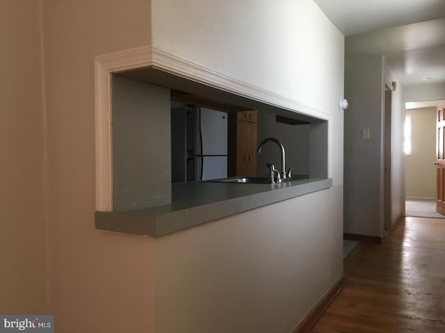 kitchen with wood finished floors, baseboards, freestanding refrigerator, and a sink