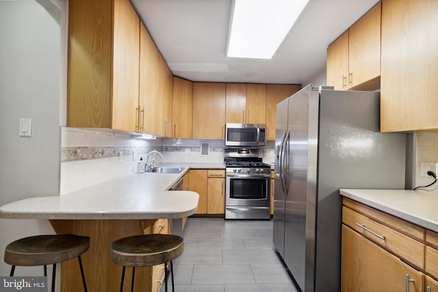 kitchen with tasteful backsplash, light tile patterned floors, a kitchen breakfast bar, stainless steel appliances, and sink