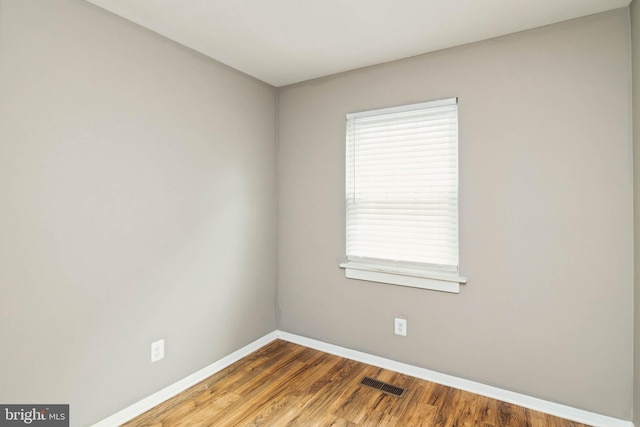 spare room featuring visible vents, baseboards, and wood finished floors