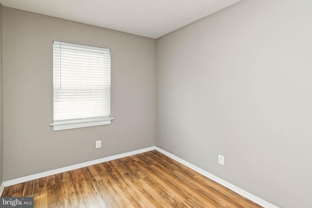 spare room featuring baseboards and wood finished floors