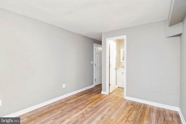 unfurnished bedroom with light wood-type flooring, baseboards, and ensuite bathroom