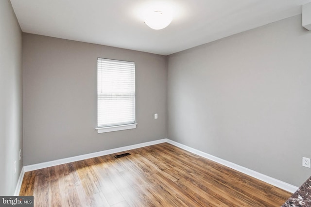 unfurnished room featuring visible vents, wood finished floors, and baseboards