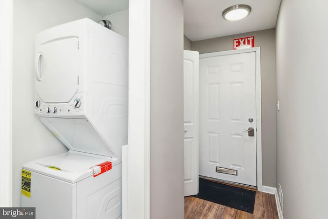 clothes washing area with dark wood-type flooring and stacked washer and dryer