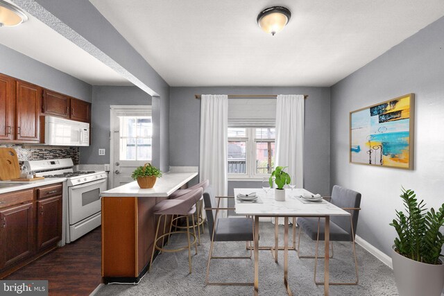 kitchen with sink, kitchen peninsula, carpet, white appliances, and backsplash