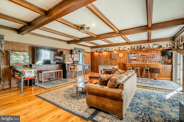 living room with beamed ceiling, hardwood / wood-style flooring, wood walls, and bar