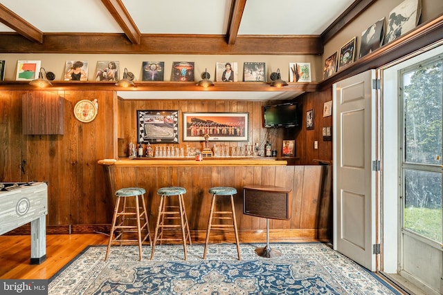 bar featuring wood walls, beamed ceiling, and light hardwood / wood-style floors