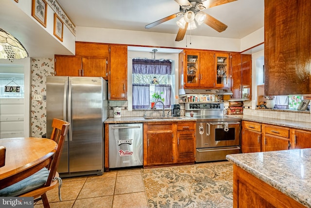 kitchen with appliances with stainless steel finishes, light stone counters, sink, and ceiling fan