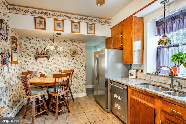 kitchen with pendant lighting, light stone countertops, stainless steel appliances, and sink