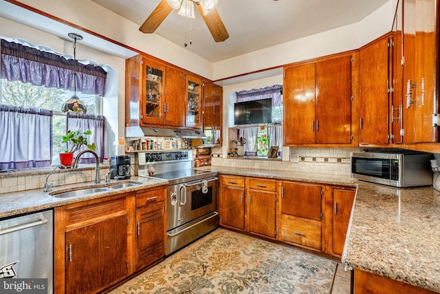 kitchen featuring tasteful backsplash, light stone counters, sink, ceiling fan, and appliances with stainless steel finishes