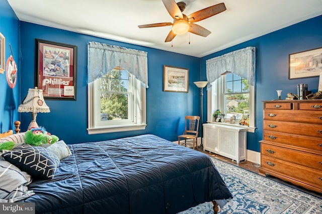 bedroom featuring ceiling fan, radiator heating unit, and hardwood / wood-style flooring